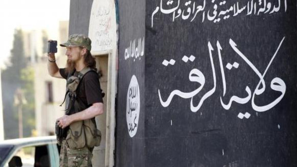 Militant Islamist fighter uses a mobile to film his fellow fighters taking part in a military parade along streets of Syria's northern Raqqa province