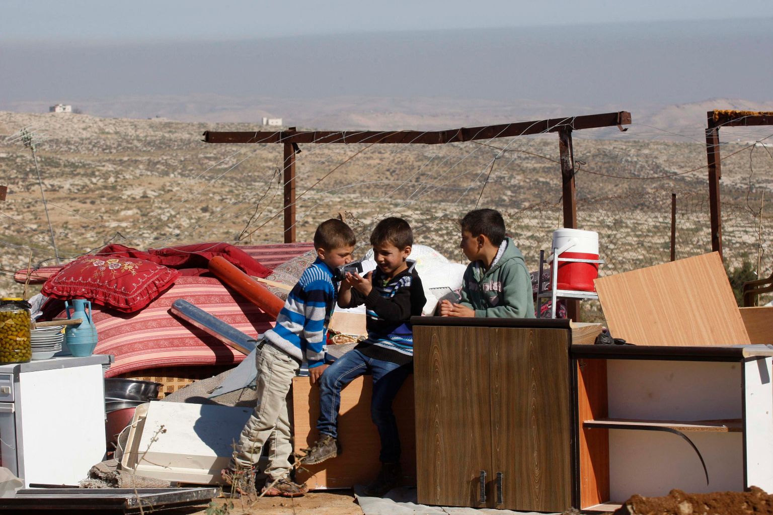 A Palestinian boy uses a digital camcorder as he sits with his family belongings after his house was demolished by the Israeli army south of the West Bank city of Hebron