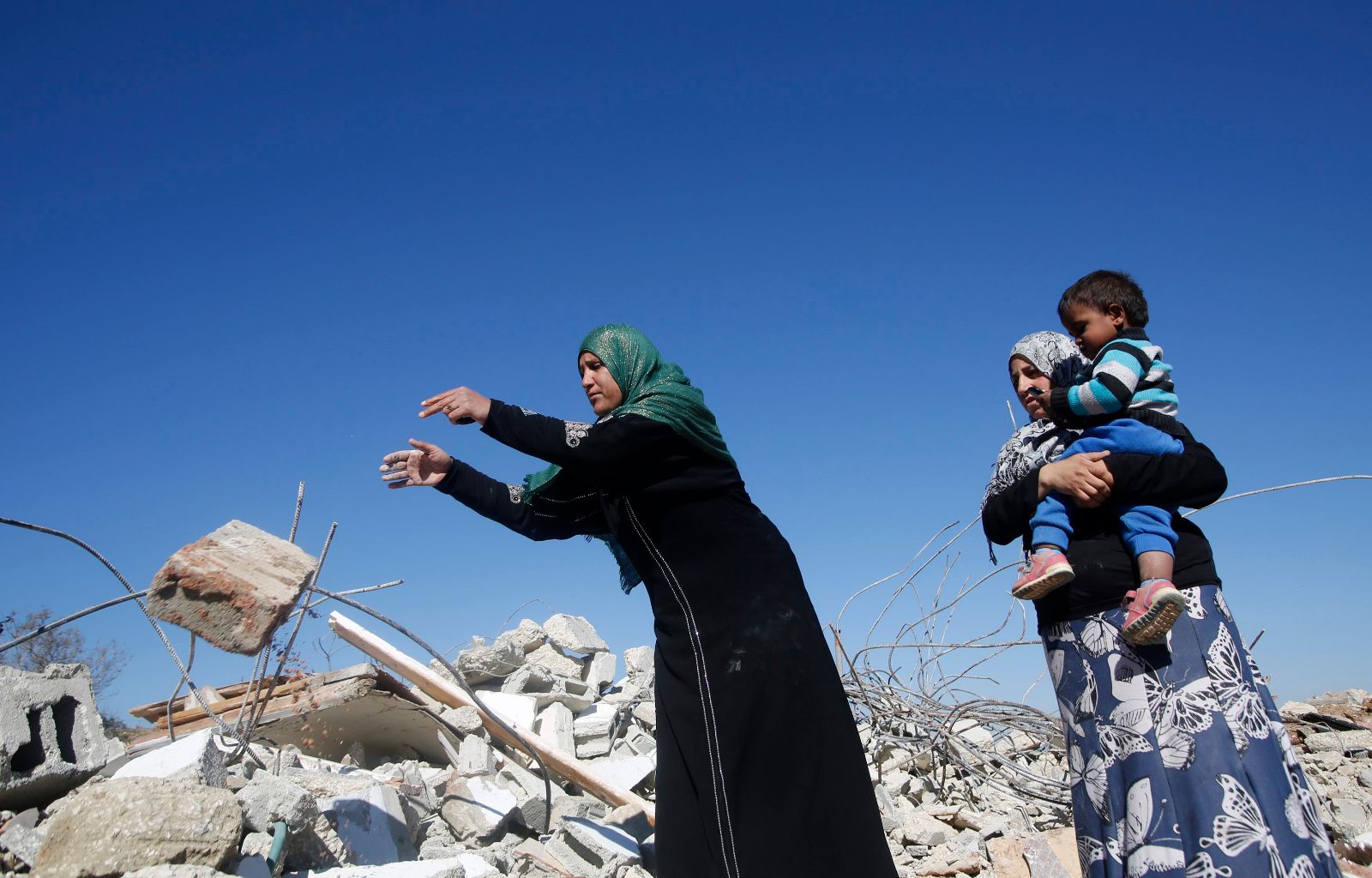 A Palestinian woman removes debris from her house after it was demolished by the Israeli army south of the West Bank city of Hebron
