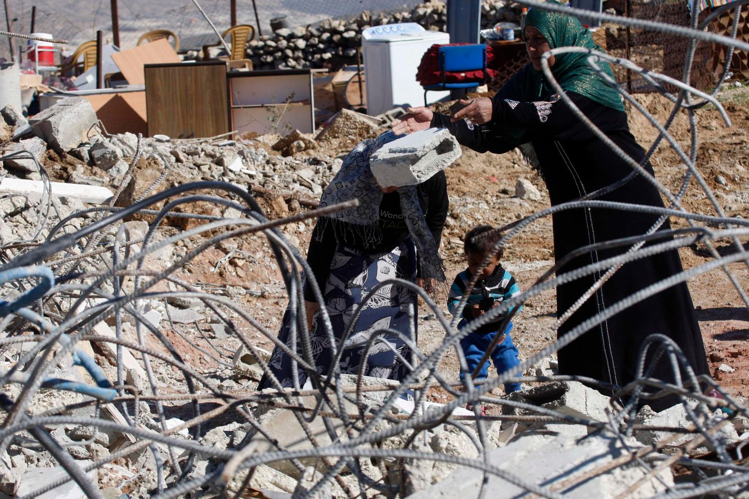 Palestinian woman removes debris from her house after it was demolished by the Israeli army south of the West Bank city of Hebron