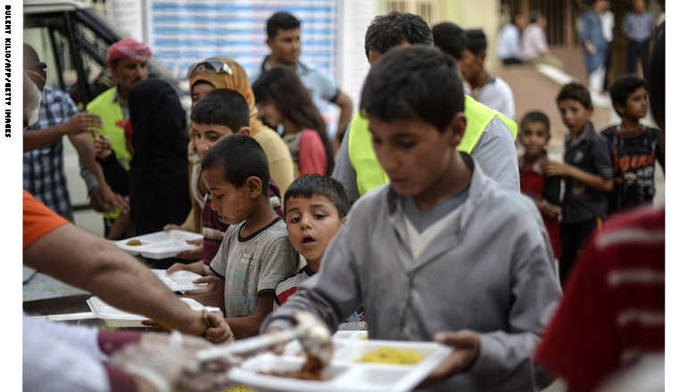 Young Syrian refugees line up for food as Syrians break their fasting on June 20, 2015 in Akcakale, in Sanliurfa province, during the holy month of Ramadan. The UN's refugee agency marked World Refugee Day on June 20 in Damascus, calling on the global community not to ignore the plight of millions of people around the world displaced by war and persecution. UNHCR says close to four million have fled the country as refugees, mainly to neighbouring countries that struggle to cope with the influx. AFP PHOTO / BULENT KILIC        (Photo credit should read BULENT KILIC/AFP/Getty Images)