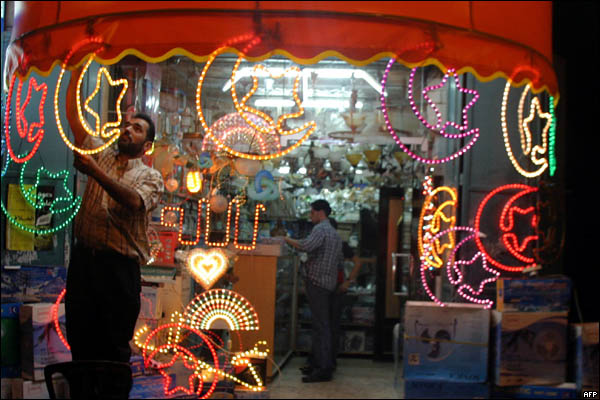 Palestinian electrician Raid Sharawi hangs decorative lamps in the shape of the Muslim crescent and star in preparation for the Muslim holy month of Ramadan outside his shop in the West Bank town of Hebron 19 September 2006. One lighting fixture costs some 50 shekels or 11 US dollars and Sharawi sells them by piece or in a string of 15 for people to hang outside their homes. Ramadan is marked by Muslims refraining from eating, drinking and sex from dawn to dusk throughout the holy month, which is expected to start around September 24 depending on sightings of the crescent moon.  AFP PHOTO/HAZEM BADER (Photo credit should read HAZEM BADER/AFP/Getty Images)