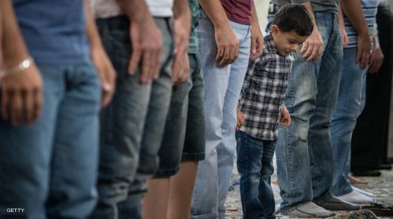 A boy stands next to his father as Muslims pray to celebrate the start of Eid al-Fitr at a mosque in downtown Sao Paulo, Brazil on August 19, 2012. Muslims around the world will celebrate this week Eid al-Fitr, marking the end of the fasting month of Ramadan. AFP PHOTO/Yasuyoshi CHIBA        (Photo credit should read YASUYOSHI CHIBA/AFP/GettyImages)