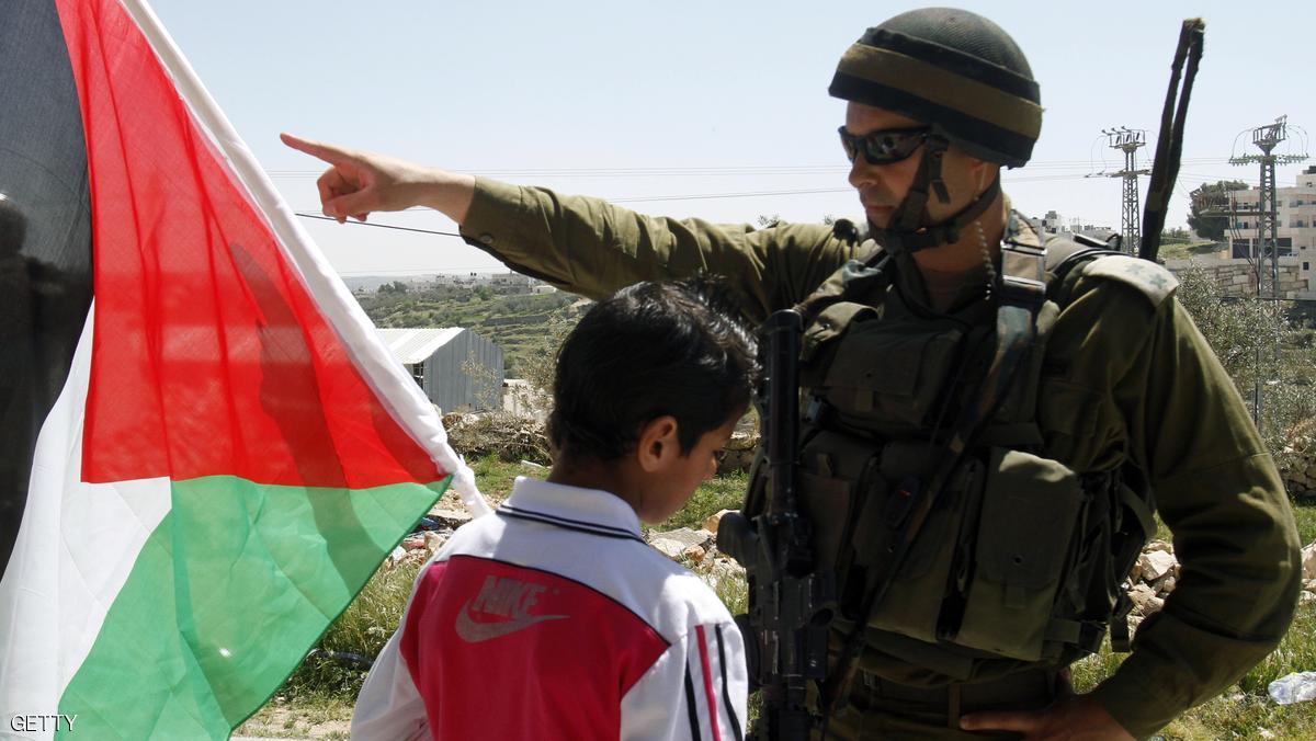 A Palestinian boy waves his national flag in front of an Israeli soldier standing guard during a weekly protest against Israel's controversial separation barrier in the West Bank village of Maasarah near Bethlehem on April 6, 2012. AFP PHOTO/MUSA AL SHAER (Photo credit should read MUSA AL SHAER/AFP/Getty Images)