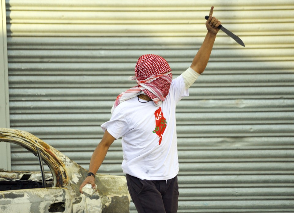 A Palestinian demonstrator raises a knife, during clashes with Israeli police, in Shuafat refugee camp in Jerusalem, Friday, Oct. 9, 2015. Recent days have seen a string of attacks by young Palestinians with no known links to armed groups who have targeted Israeli soldiers and civilians at random, complicating Israeli efforts to contain the violence, which has been linked to tensions over a sensitive Jerusalem holy site. (AP Photo/Mahmoud Illean)