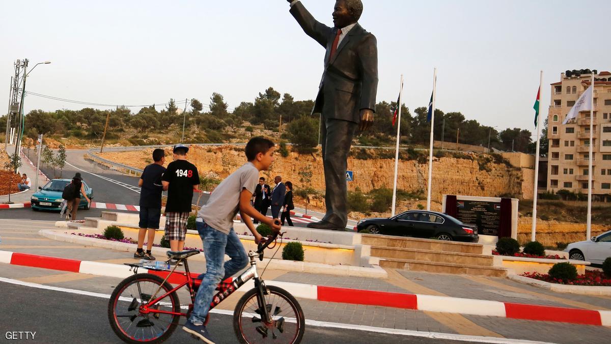 A Palestinian boy rides his bicycle past a giant statue of Nelson Mandela following its inauguration ceremony in the West Bank city of Ramallah on April 26, 2016. Palestinians inaugurated the statue of Mandela donated by the South African city of Johannesburg to their political capital. The six-metre (20-foot) two-tonne bronze statue was a gift from Johannesburg with which Ramallah is twinned. / AFP / ABBAS MOMANI (Photo credit should read ABBAS MOMANI/AFP/Getty Images)