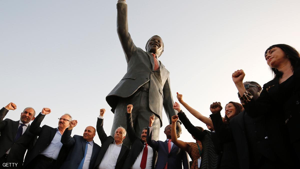 Palestinian and South African officials pose in front of a giant statue of Nelson Mandela during its inauguration ceremony in the West Bank city of Ramallah on April 26, 2016. Palestinians inaugurated the statue of Mandela donated by the South African city of Johannesburg to their political capital. The six-metre (20-foot) two-tonne bronze statue was a gift from Johannesburg with which Ramallah is twinned. / AFP / ABBAS MOMANI (Photo credit should read ABBAS MOMANI/AFP/Getty Images)