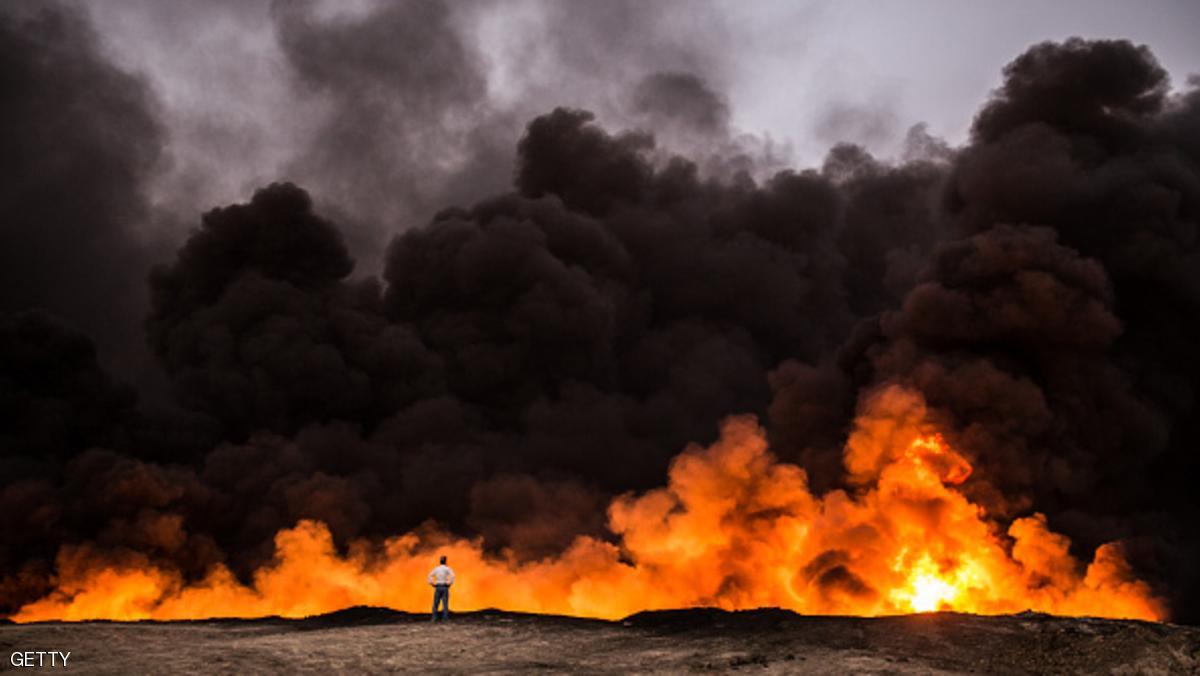 TOPSHOT - A man stands in front of a fire from oil that has been set ablaze in the Qayyarah area, some 60 kilometres (35 miles) south of Mosul, on October 19, 2016, during an operation by Iraqi forces against Islamic State (IS) group jihadists to retake the main hub city. In the biggest Iraqi military operation in years, forces have retaken dozens of villages, mostly south and east of Mosul, and are planning multiple assaults for October 20. / AFP / YASIN AKGUL        (Photo credit should read YASIN AKGUL/AFP/Getty Images)