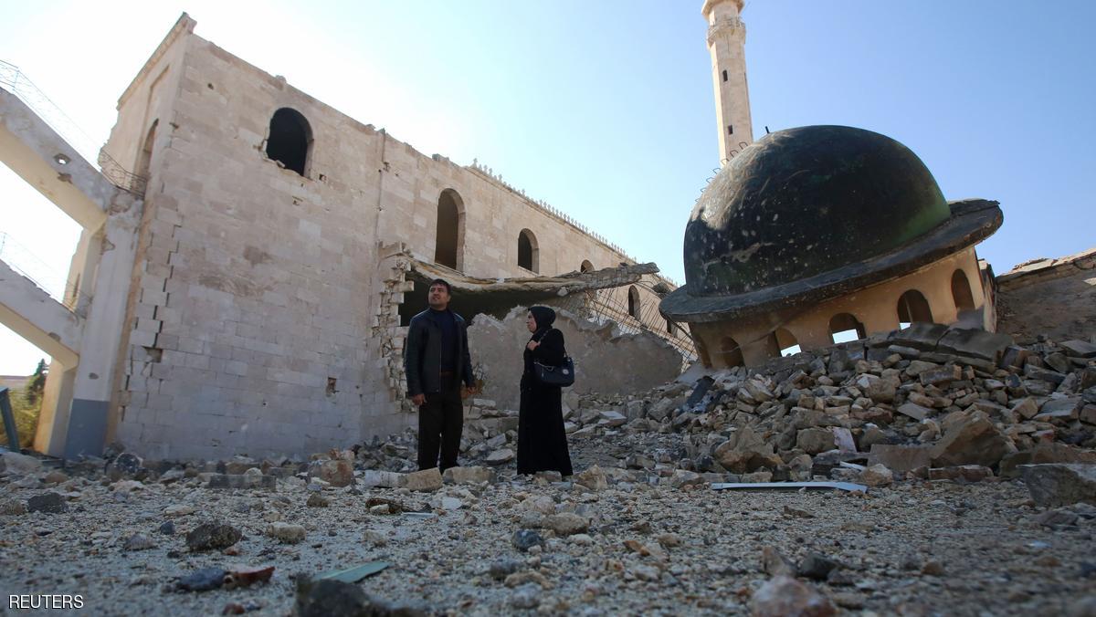 Kefa Jawish (R) and her husband Tajeddin Ahmed walk among the ruins of a destroyed mosque in Aleppo's Hanano district as they head to check their house for the first time in four years in the city's northeastern Haydariya neighbourhood on December 4, 2016. Jawish was among hundreds of Syrians returning to east Aleppo in recent days after the army recaptured large swathes of the city from rebels and encouraged residents to visit neighbourhoods and homes they left years earlier. / AFP / Youssef KARWASHAN / TO GO WITH AFP STORY BY RIM HADDAD (Photo credit should read YOUSSEF KARWASHAN/AFP/Getty Images)