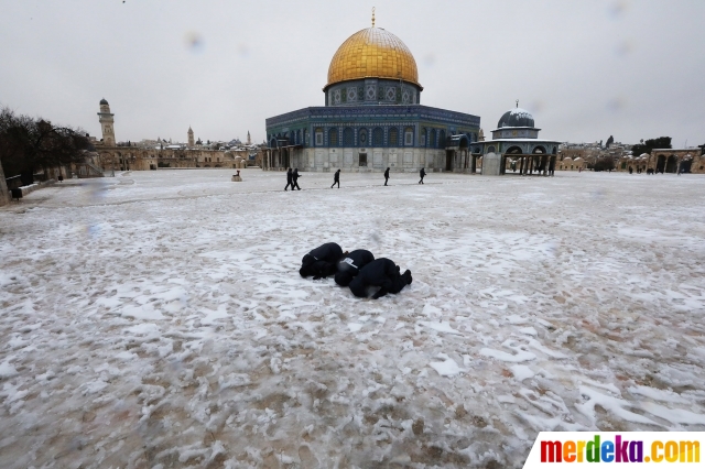 Seorang warga melaksanakan salat di halaman Kubah Shakhrakh, kompleks Masjidil Aqsa, yang diselimuti salju, Jerusalem, Kamis (18/2/2021).