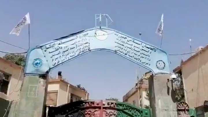Bendera Taliban dikibarkan di gerbang markas polisi di Kota Ghazni, Afganistan, 12 Agustus 2021. Situasi itu menyebabkan ribuan keluarga meninggalkan daerah mereka untuk mencari tempat yang lebih aman di Kabul dan kota-kota lain. Taliban Handout/via REUTERS