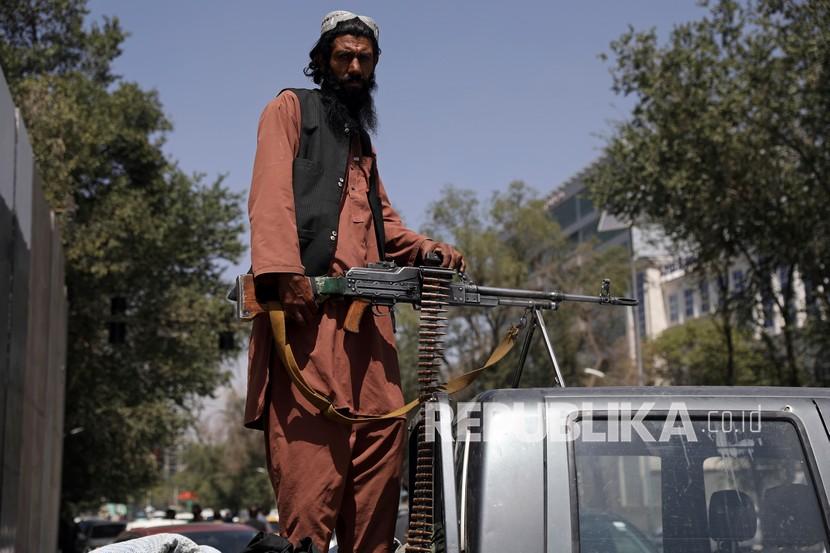  Seorang pejuang Taliban duduk di belakang kendaraan dengan senapan mesin di depan gerbang utama menuju istana kepresidenan Afghanistan, di Kabul, Afghanistan, Senin, 16 Agustus 2021. Militer AS telah mengambil alih wilayah udara Afghanistan saat berjuang untuk mengelola evakuasi yang kacau setelah Taliban masuk ke ibu kota. 