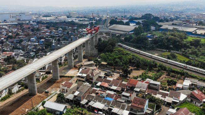 Kereta api melintas di dekat proyek konstruksi kereta api cepat Jakarta-Bandung di Lembah Teratai, Kabupaten Bandung Barat, Jawa Barat, Minggu (8/8/2021). ANTARA FOTO/Raisan Al Farisi
